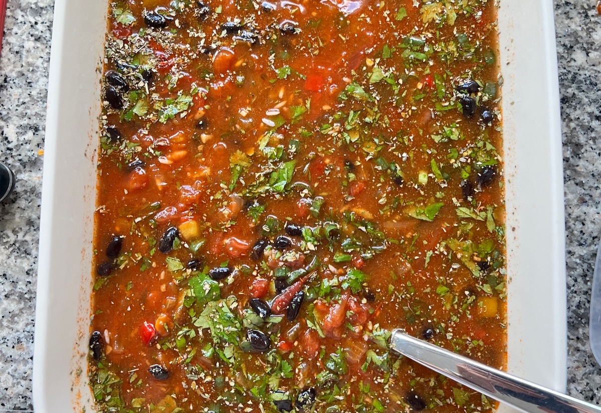 Black beans, seasonings, cilantro, salsa, rice, and broth mixed in casserole dish for Salsa Chicken Casserole Recipe.