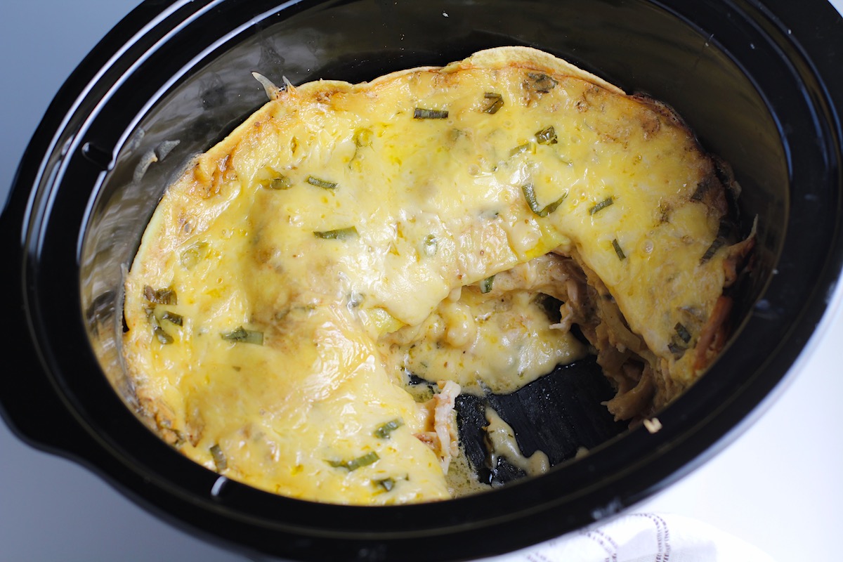 Overhead shot of the cooked crockpot white chicken enchilada casserole with a piece removed from the side.