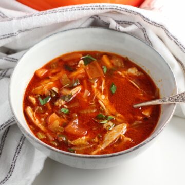 Spanish Chicken Soup in a bowl with a spoon on table.
