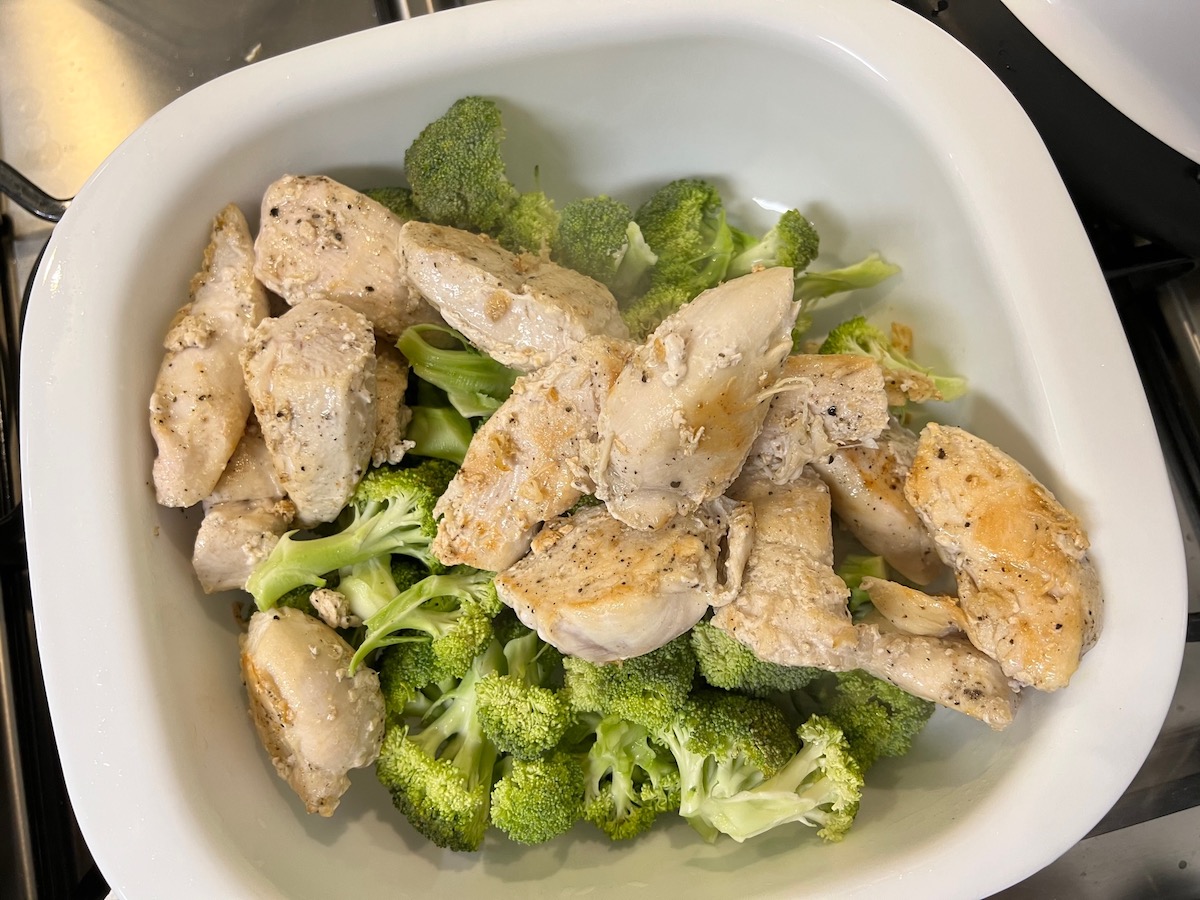 Browned chicken pieces and raw broccoli florets in a casserole dish for Chicken Divan Curry Casserole Recipe.