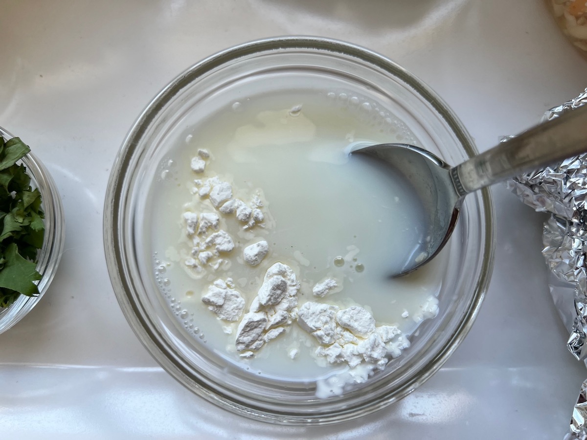 Spoon mixing cornstarch into cold milk for Low Carb Cauliflower Rice Chicken Casserole.