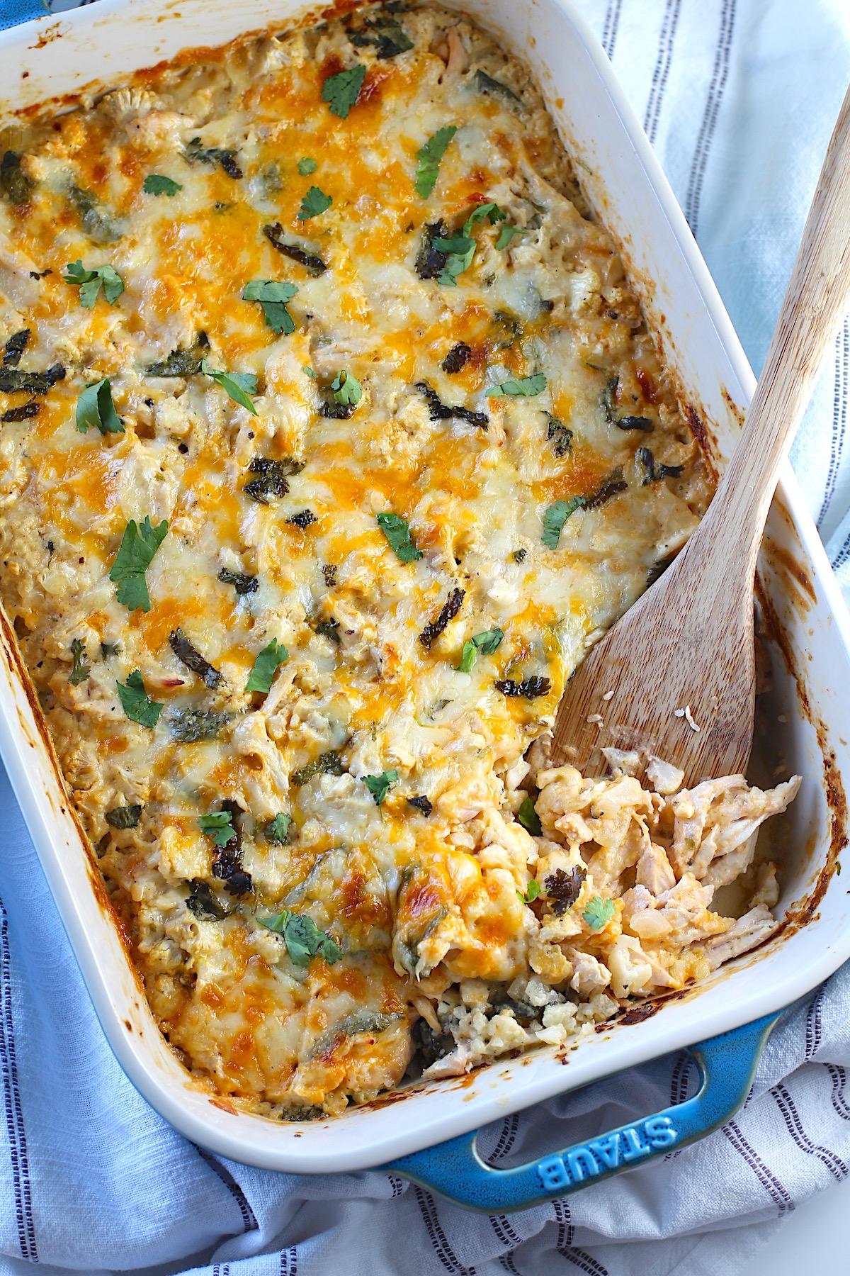 Low carb Chicken Cauliflower Rice Bake in a casserole dish with a spatula scooping it in the corner.