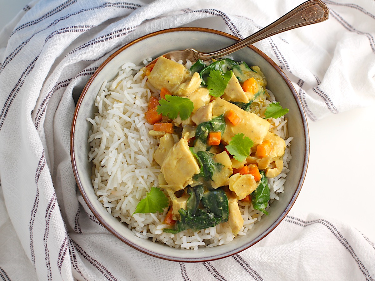 Crockpot Thai Chicken Curry over rice in a bowl with fork.