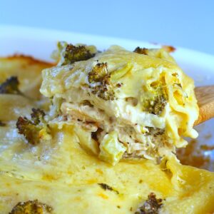 Broccoli and Chicken Lasagna in casserole dish with spatula scooping up a piece from the corner showing creamy and cheesy filling.