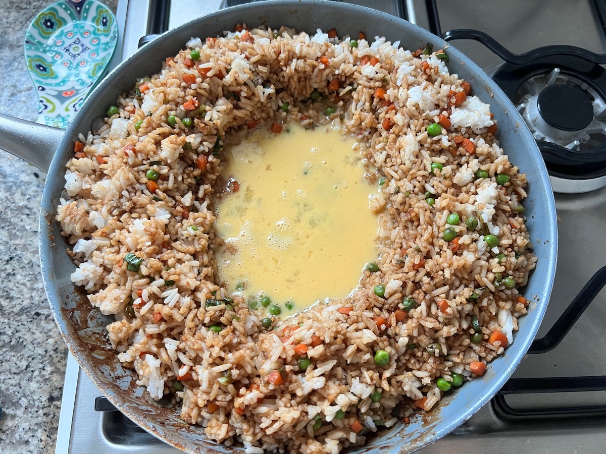 Fried Rice in a pan pushed out to the sides and beaten eggs poured into the center of the pan hold for Shrimp and Chicken Fried Rice recipe.