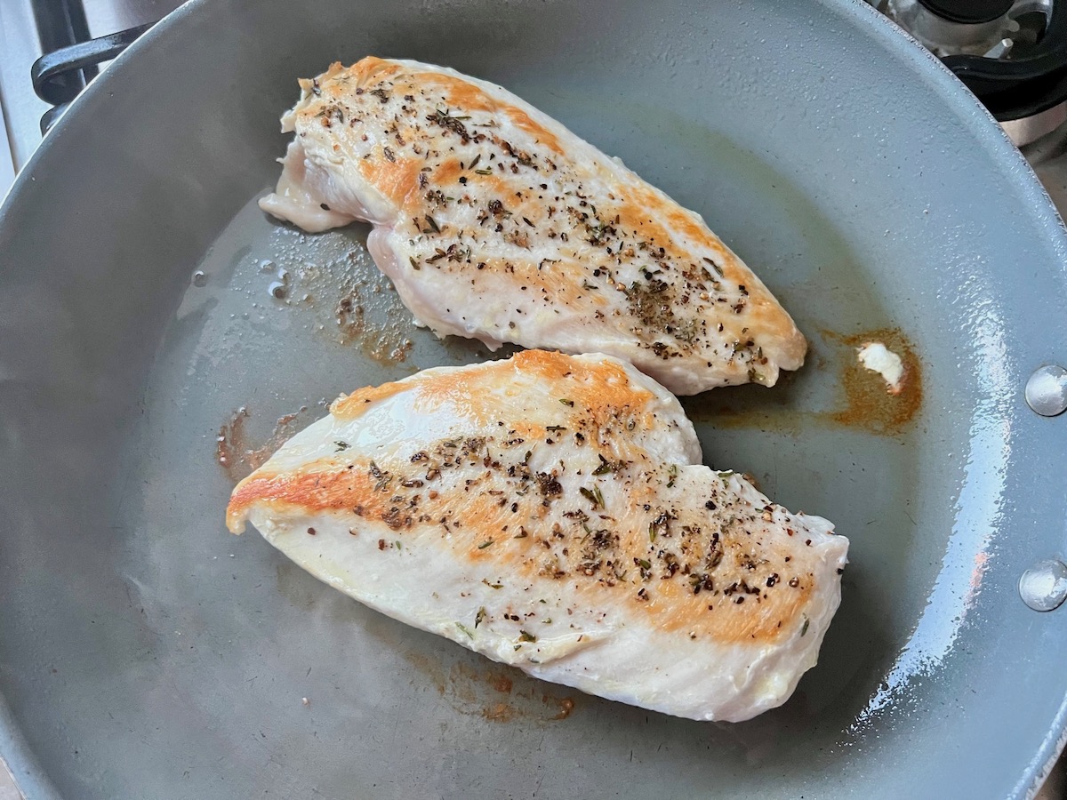 Golden fried chicken breasts in a skillet.