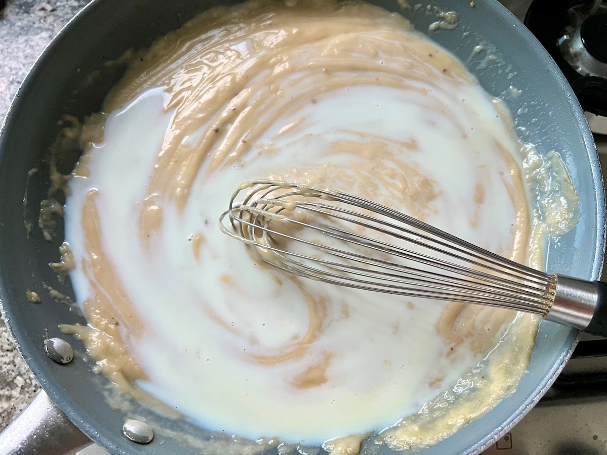 Roux being stirred together in a skillet with a wire whisk.