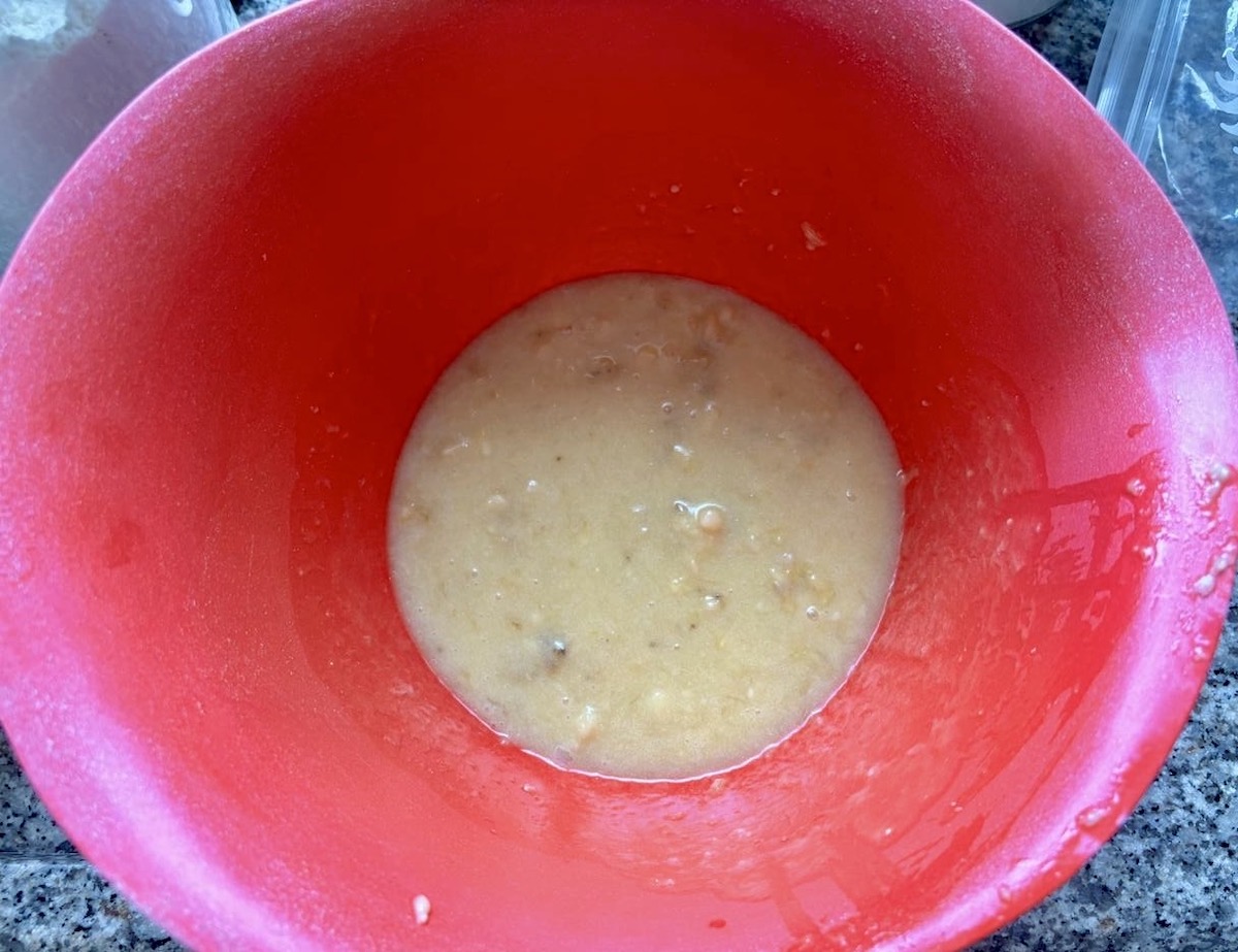 Oat bran and milk combined in a mixing bowl to prepare oat banana chocolate chip muffins.
