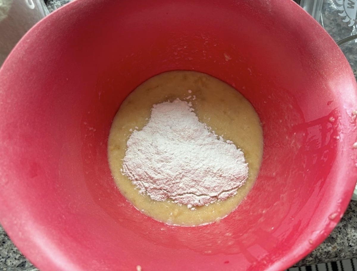 Dry and wet ingredients being combined in a mixing bowl for oat banana chocolate chip muffins.