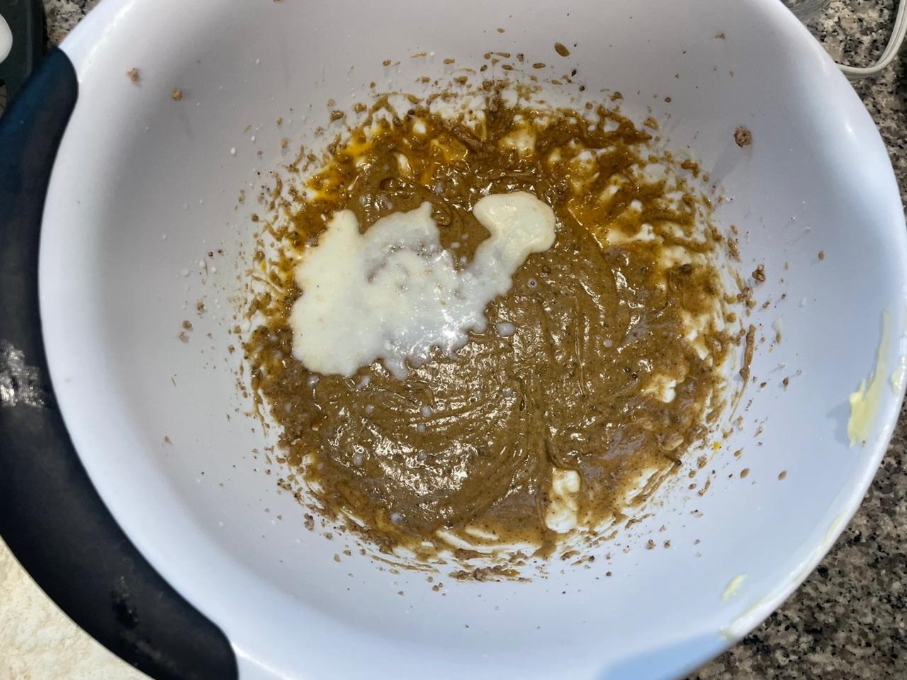 A little bit of buttermilk added to the butter-sugar-egg mixture in a bowl for the Strawberry Banana Cake recipe.