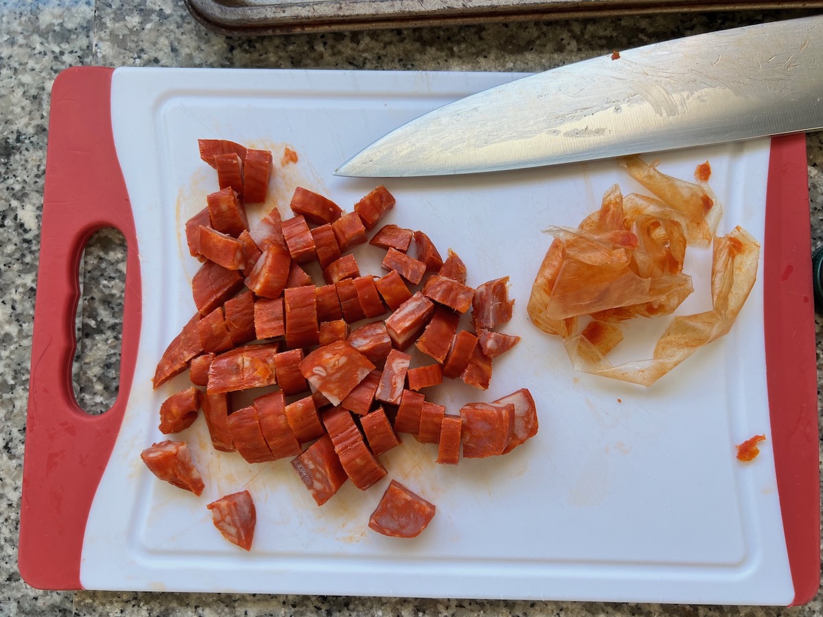 Spanish chorizo diced on cutting board with the casing peeled off next to it and a knife for the Pasta with chorizo and chicken recipe.