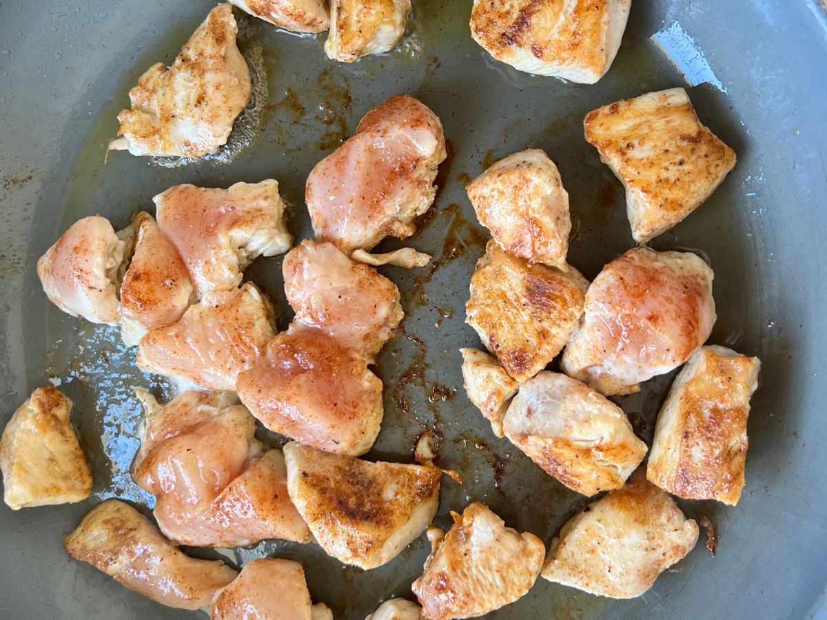 Seasoned chicken cubes in a skillet, preparing to be used in pasta with chorizo and chicken.