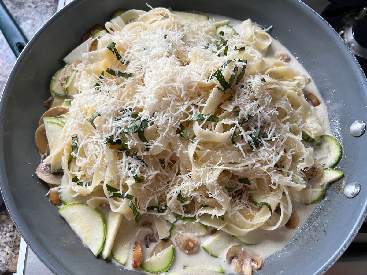 Shaved parmesan and ribbons of fresh basil served over pasta with zucchini and mushrooms.