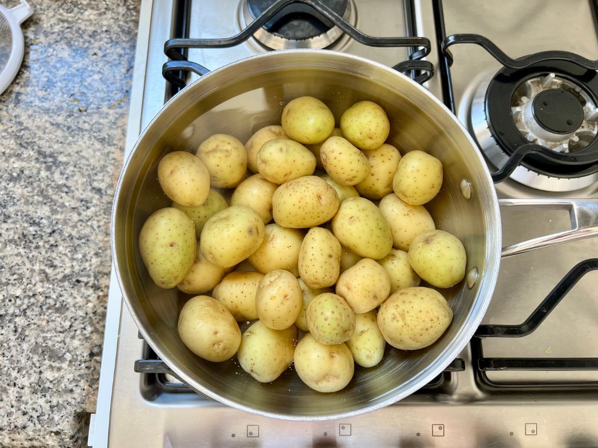 Pot of water with baby potatoes cooking in it.