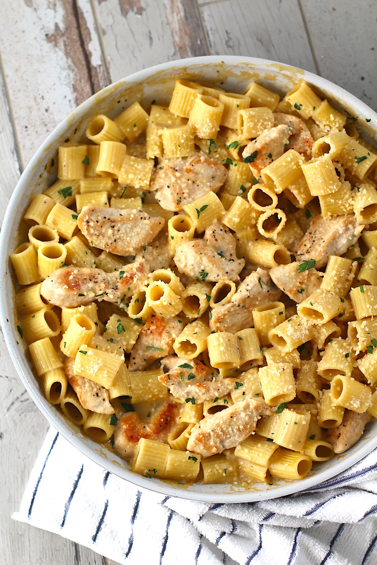 Garlic Chicken Parmesan Pasta in a skillet on table with dish towel.