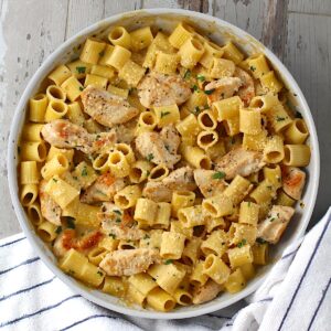 Garlic Chicken Parmesan Pasta in a skillet on table with dish towel.