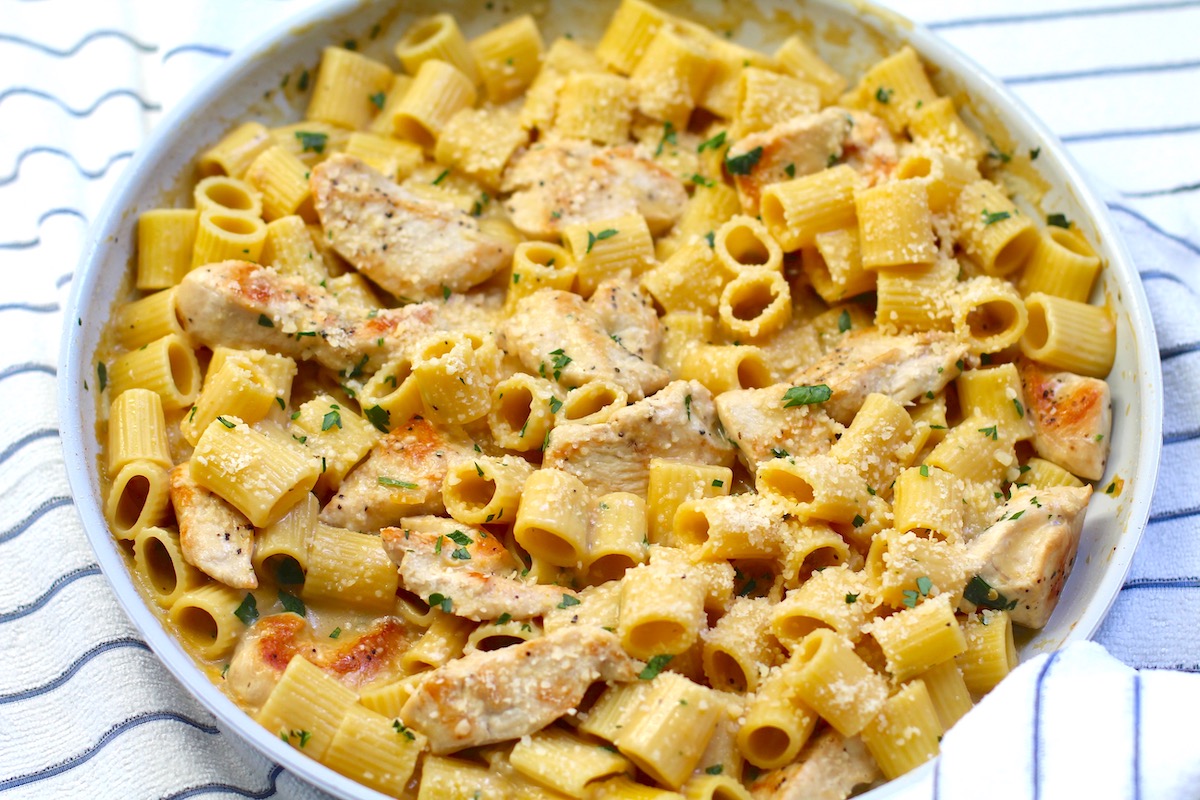 Garlic Chicken Parmesan Pasta in a skillet on table with dish towel.