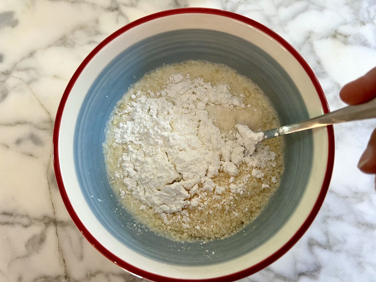 Parmesan cheese milk slurry in a bowl with a fork in the mixture to stir.