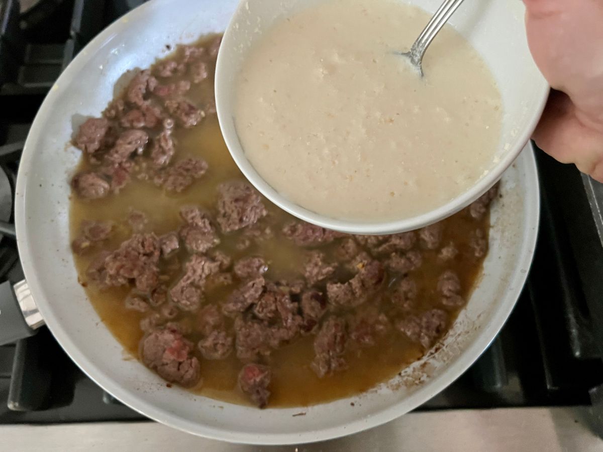 Parmesan cheese cornstarch slurry being stirred into the ground beef mixture.