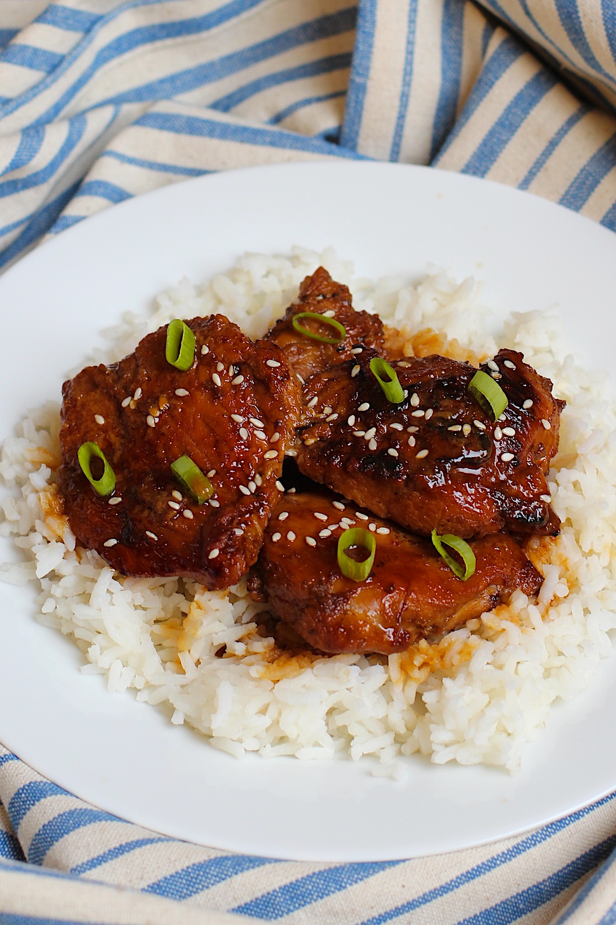 Honey Ginger Chicken served over white rice with sliced scallions and sesame seeds on top.