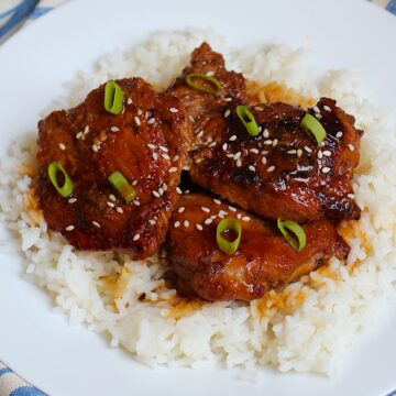 Honey Ginger Chicken served over white rice with sliced scallions and sesame seeds on top.