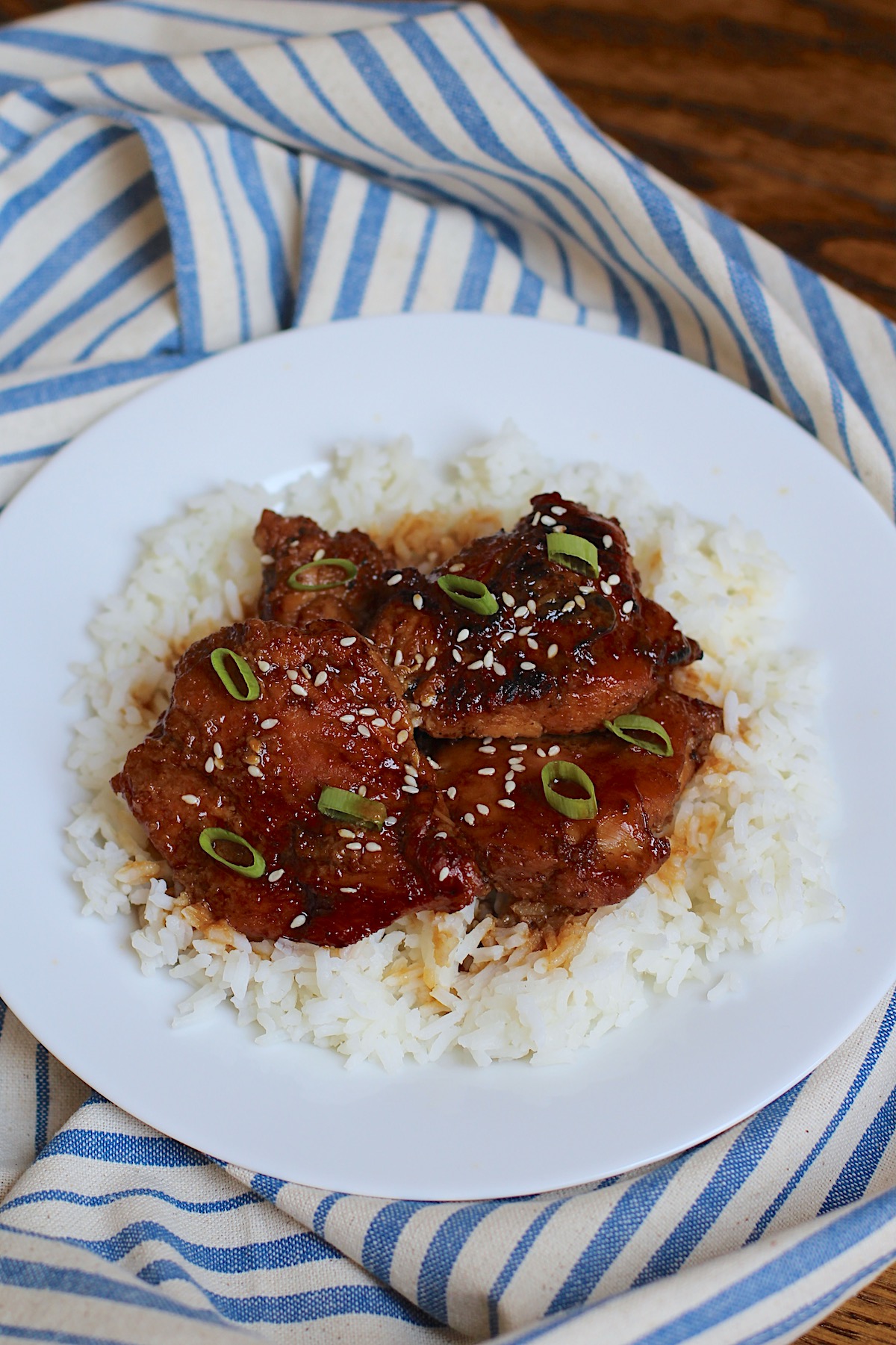 Honey Ginger Chicken served over white rice with sliced scallions and sesame seeds on top.