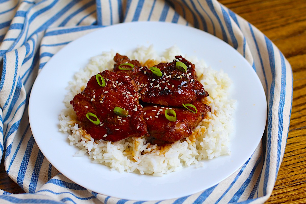 Honey Ginger Chicken served over white rice with sliced scallions and sesame seeds on top.