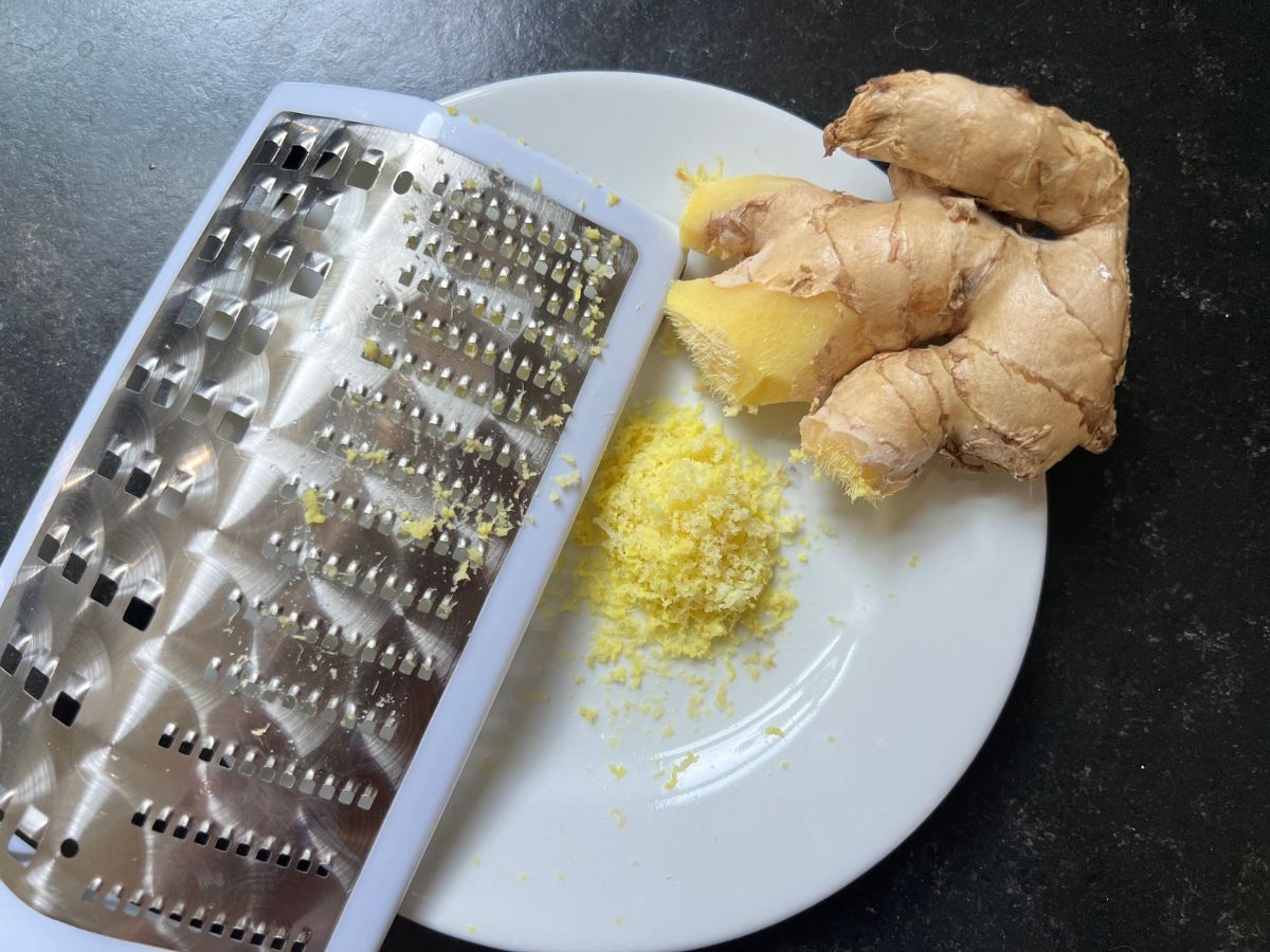 Ginger being grated over a plate.