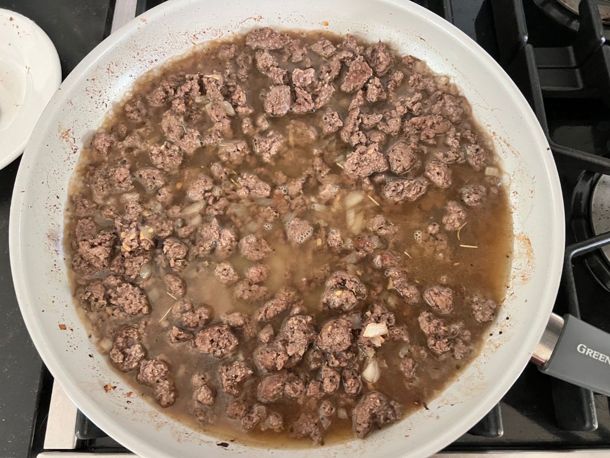 Beef stock and pasta water added to beef mixture in skillet.