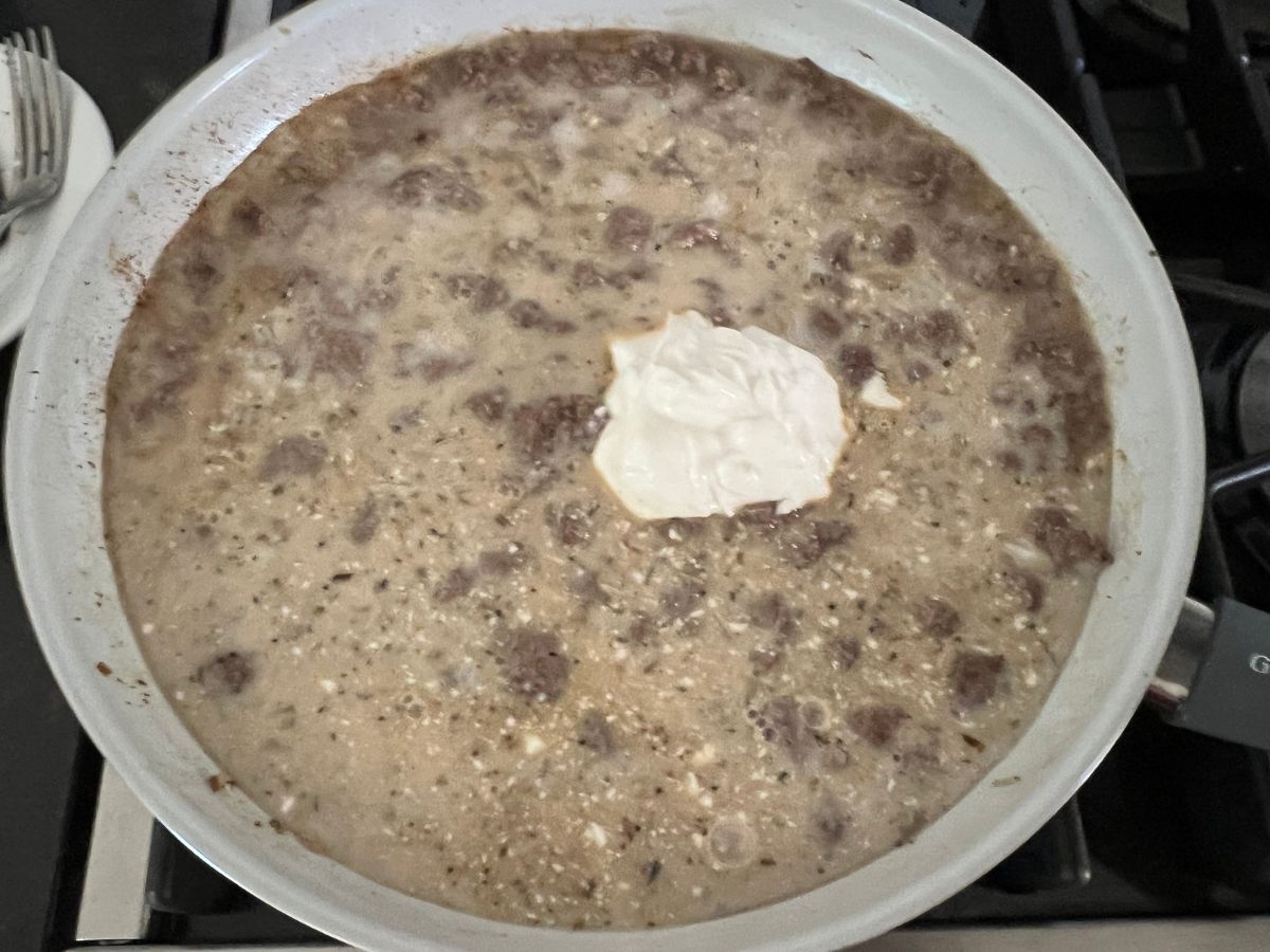 Cornstarch and sour cream added to ground beef mixture in a skillet.