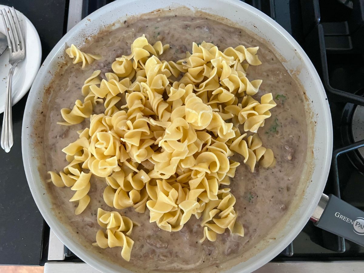 Cooked egg noodles added to ground beef mixture, ready to serve.