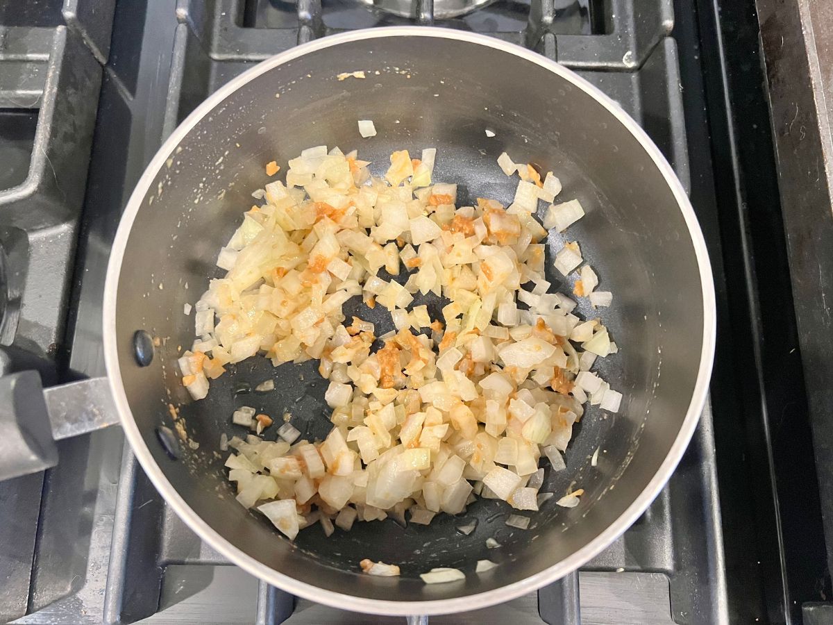 Onions and minced garlic sauteing in a saucepan.