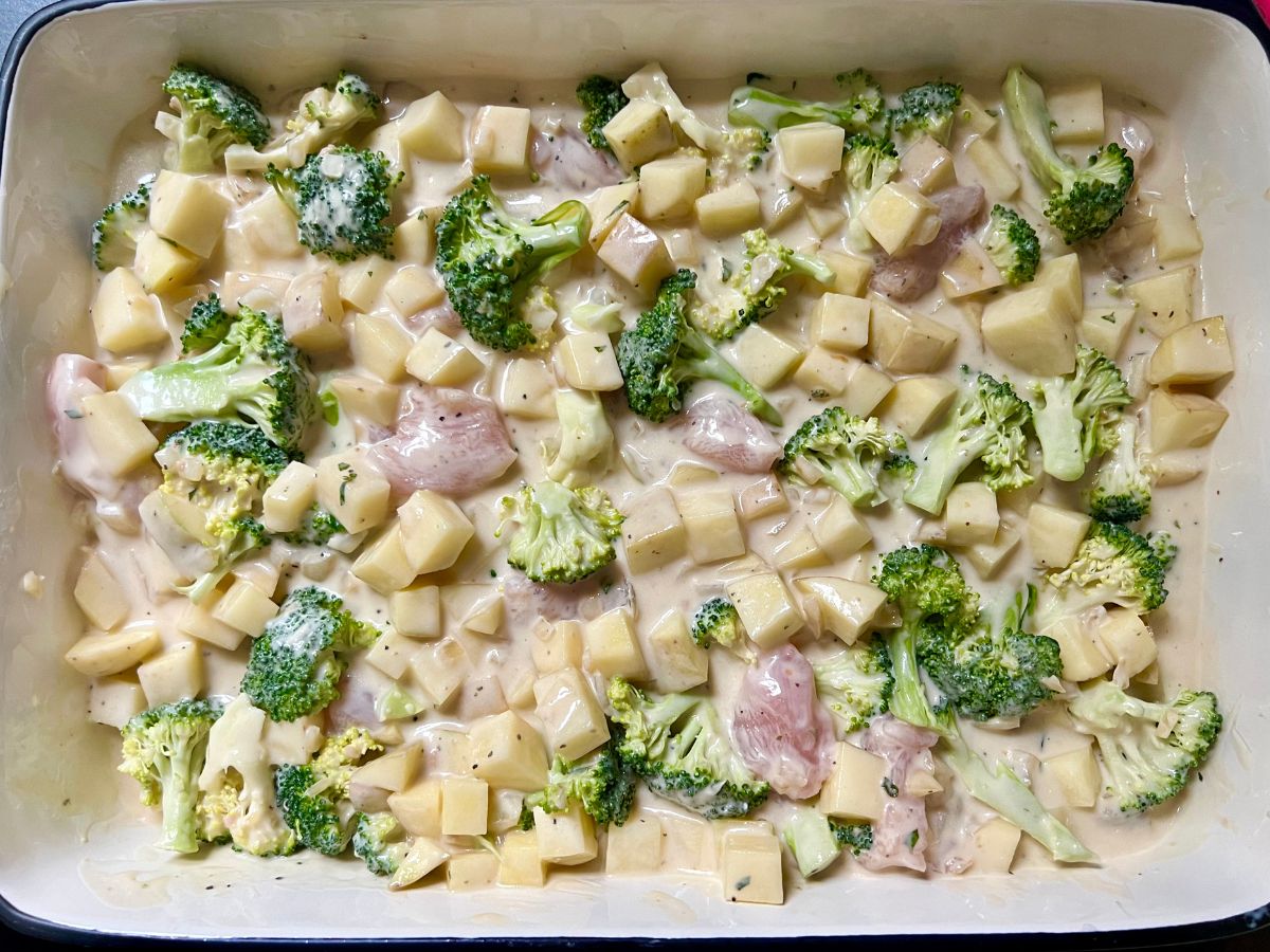 Homemade sauce poured over the chicken, potatoes and broccoli in a baking dish.