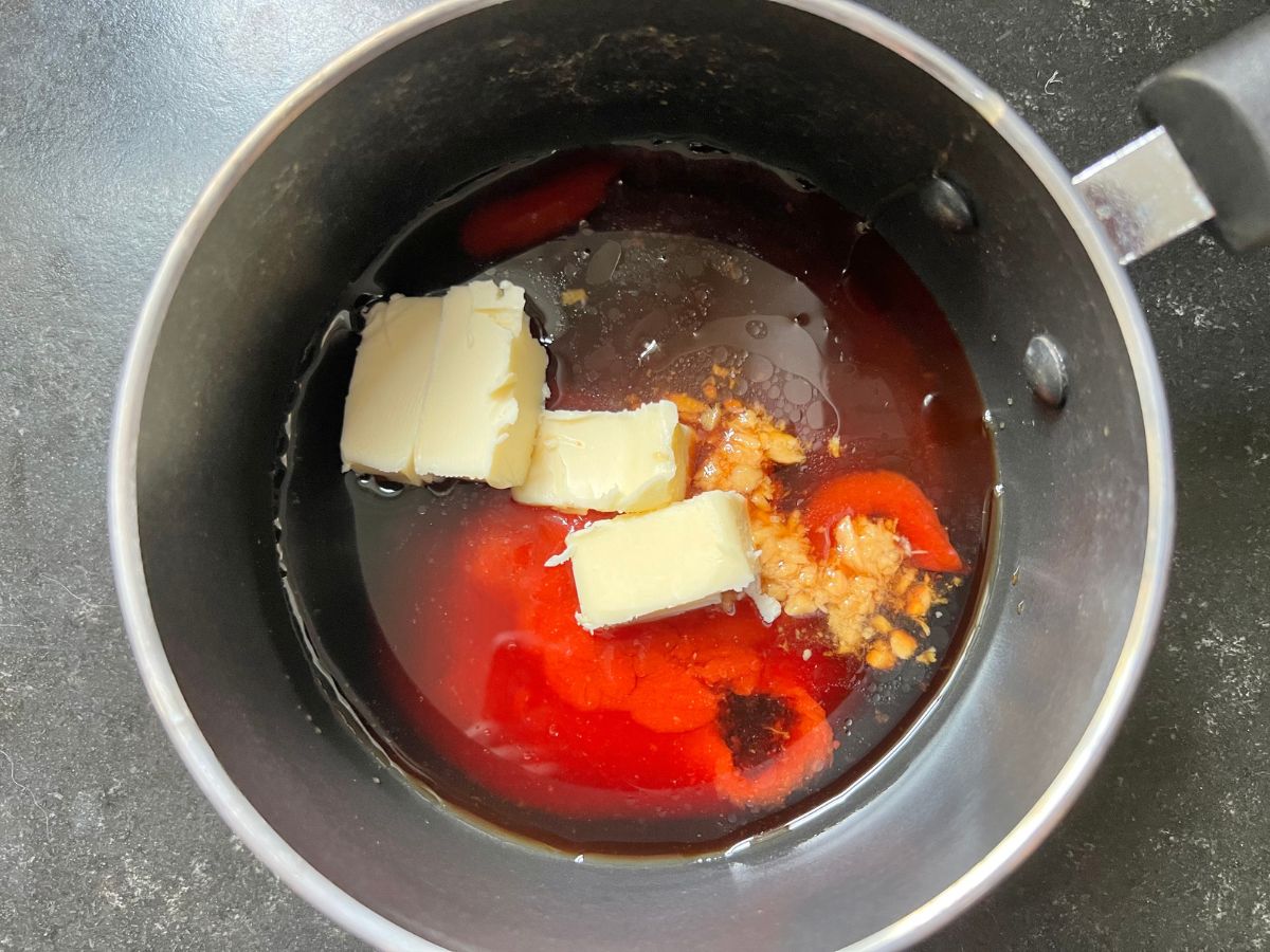 Ketchup, butter, garlic, rice vinegar and soy sauce added to a pan.