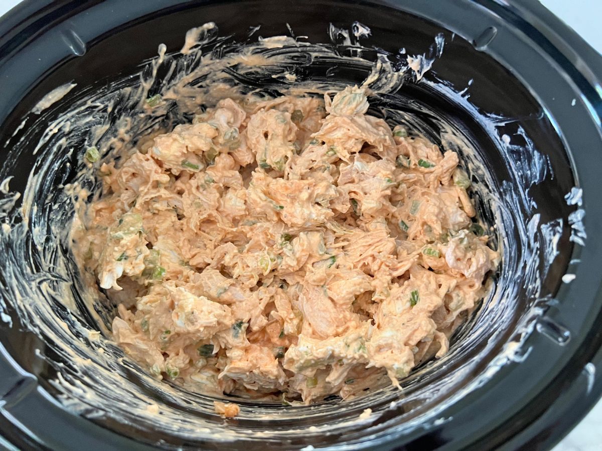 Buffalo chicken dip in a slow cooker creamed together.