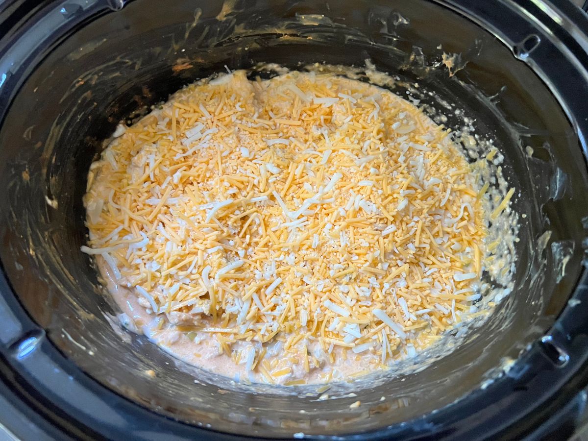 Shredded cheese sprinkled over buffalo chicken dip mixture.