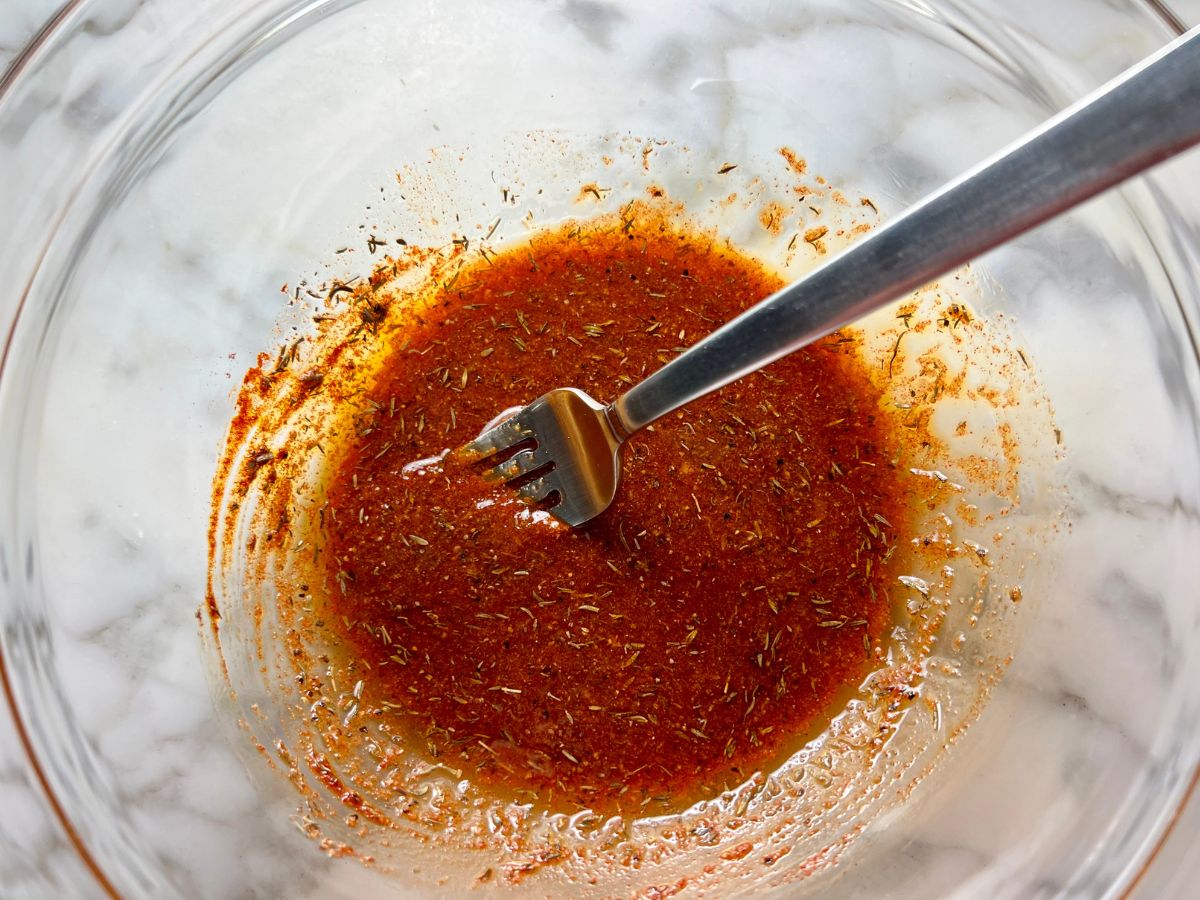Seasoning for chicken, potatoes and veggies in a mixing bowl.