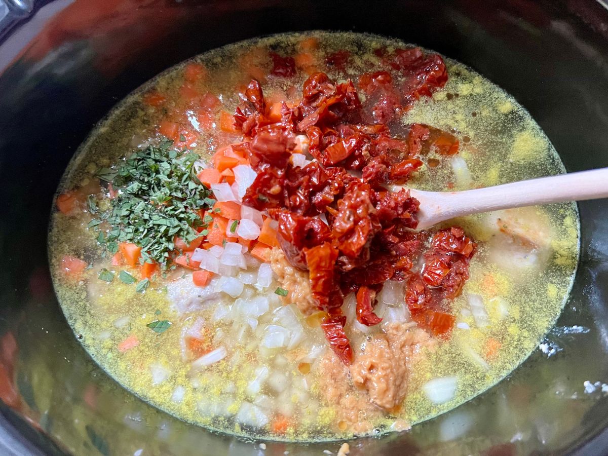 Veggies, sun-dried tomatoes and broth added to meatballs in a slow cooker.