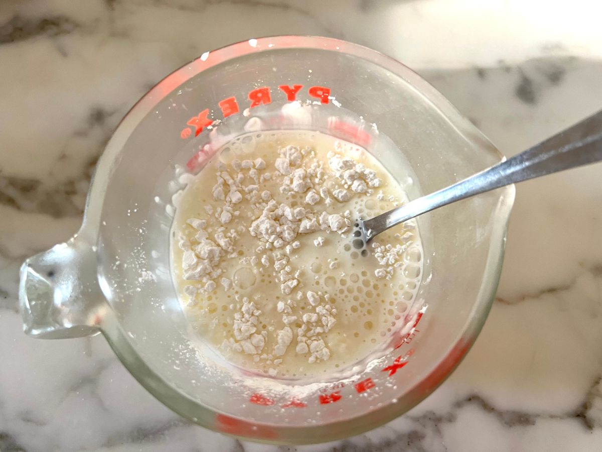 Cornstarch slurry in a glass measuring cup.