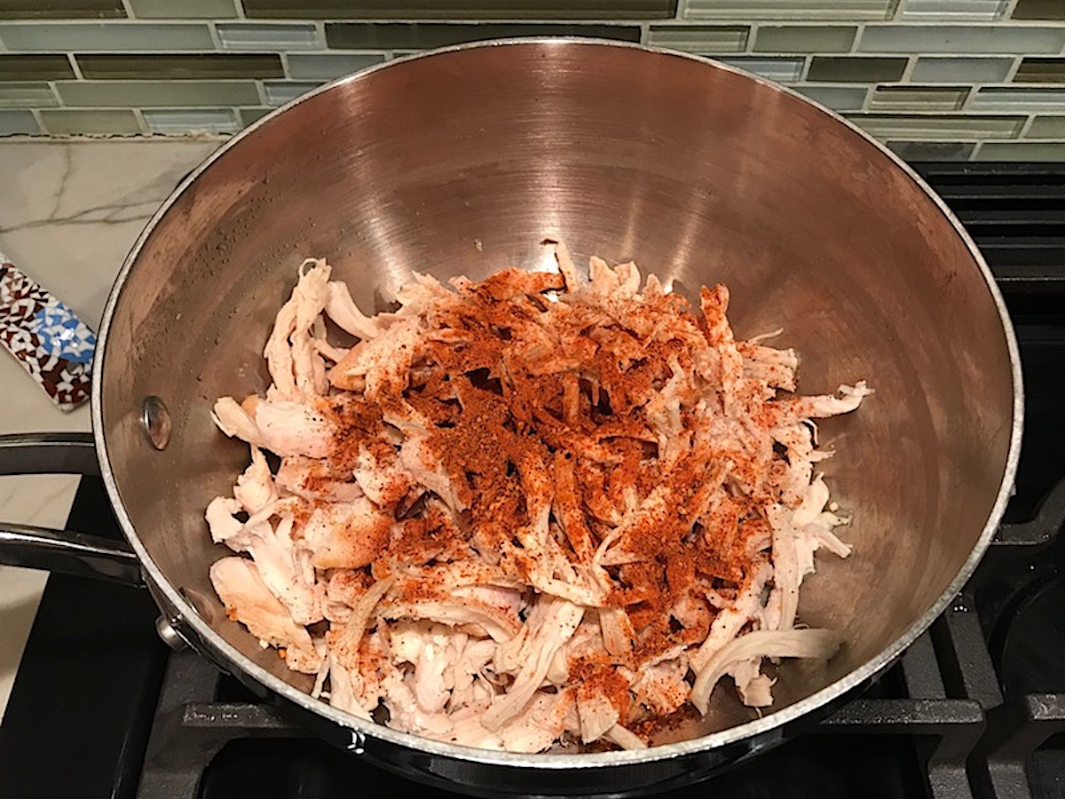 Taco Seasoning for Chicken Recipe showing the taco blend added to a pot of cooked shredded chicken.