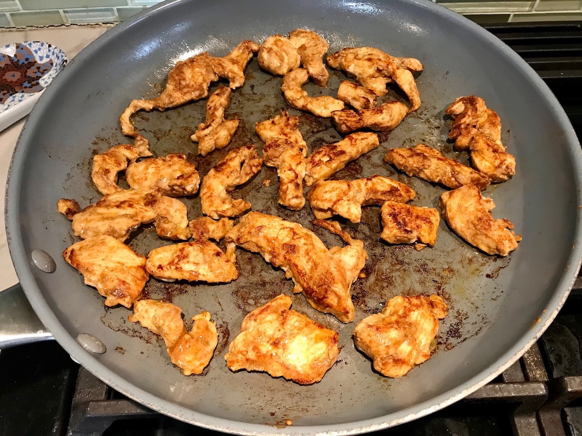 Taco Seasoning for Chicken Recipe showing the taco blend added to chicken breast pieces that are cooking in a frying pan.