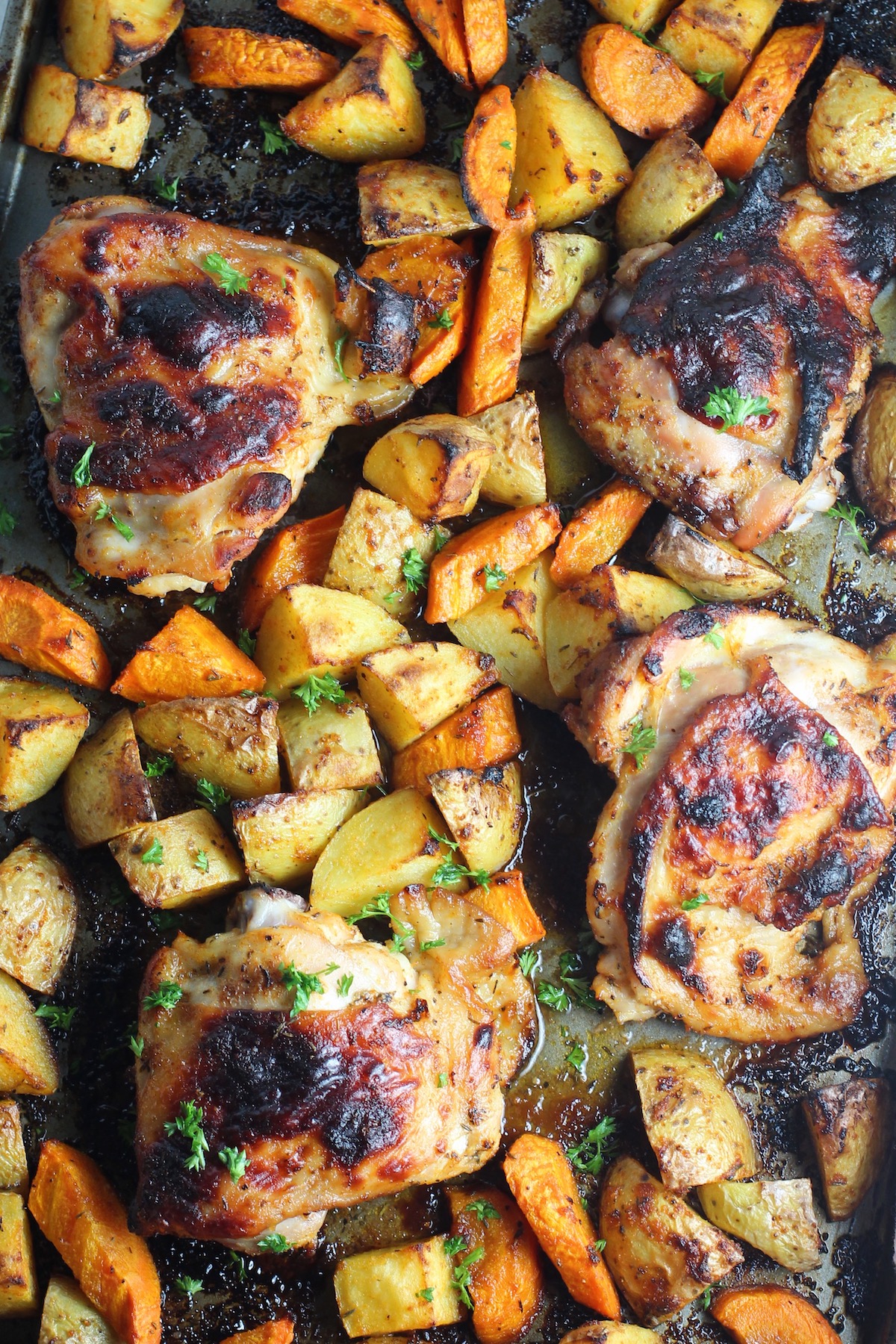 Tray baked Chicken Thighs and Potatoes on the pan perfectly  browned glistening.