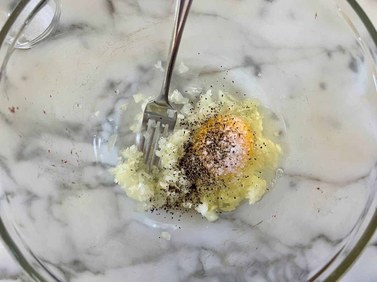 Egg, onion mixture, salt, pepper added to a glass bowl.