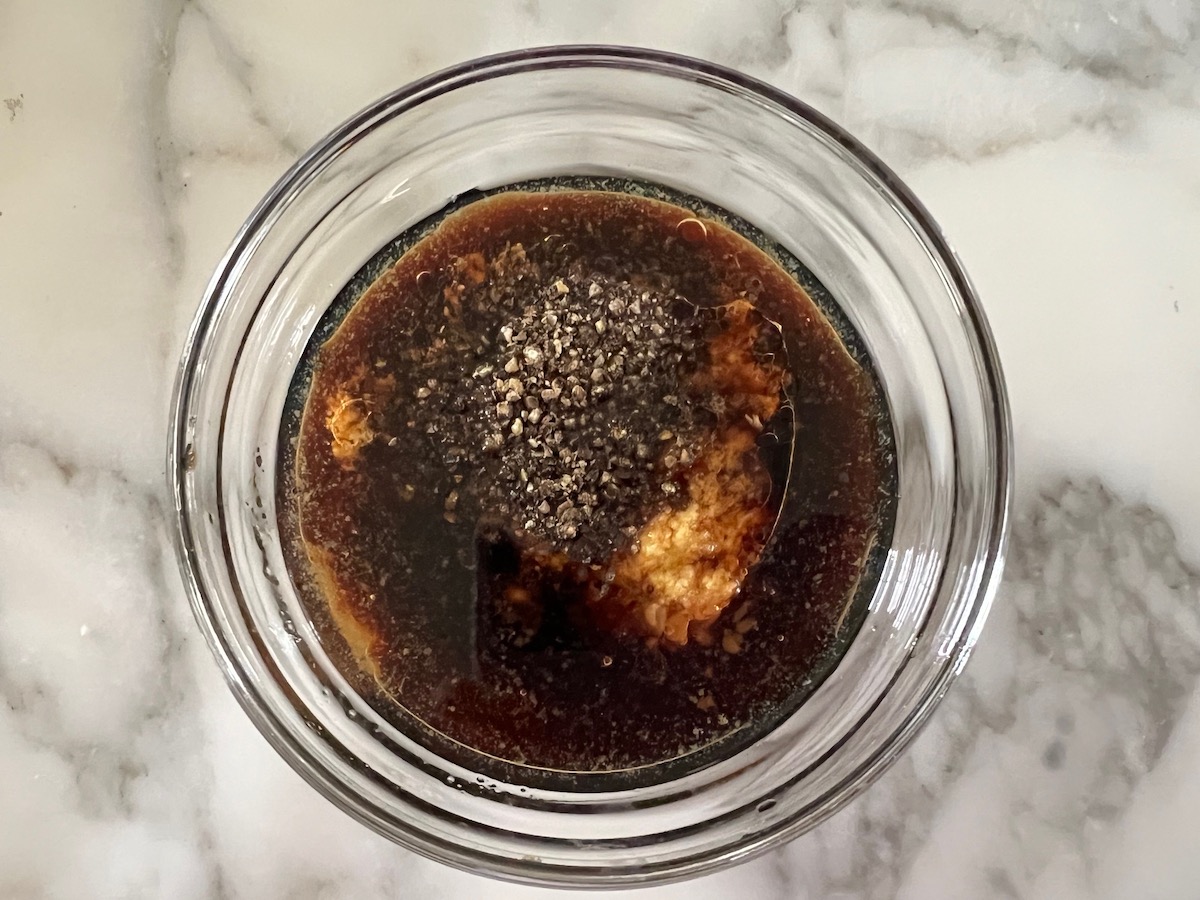 Ingredients for sauce in a small clear glass bowl for Black Pepper Beef Stir Fry with onions.
