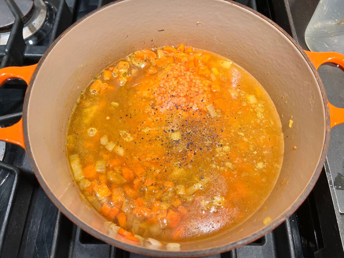 Broth and red lentils added to the sauteed vegetables.