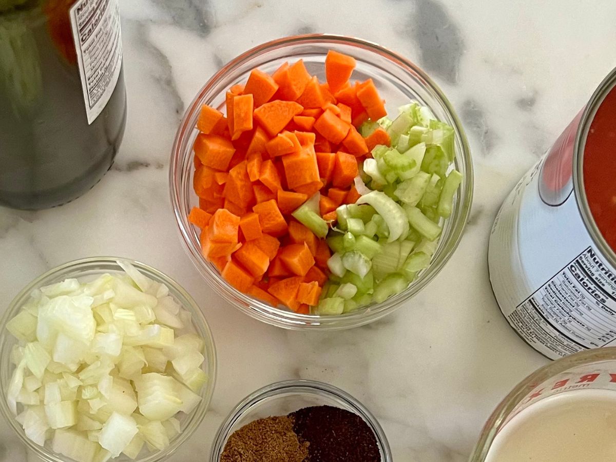 Diced onions in a small bowl and chopped carrots and celery in another small bowl to prepare for chicken chili with ground chicken.