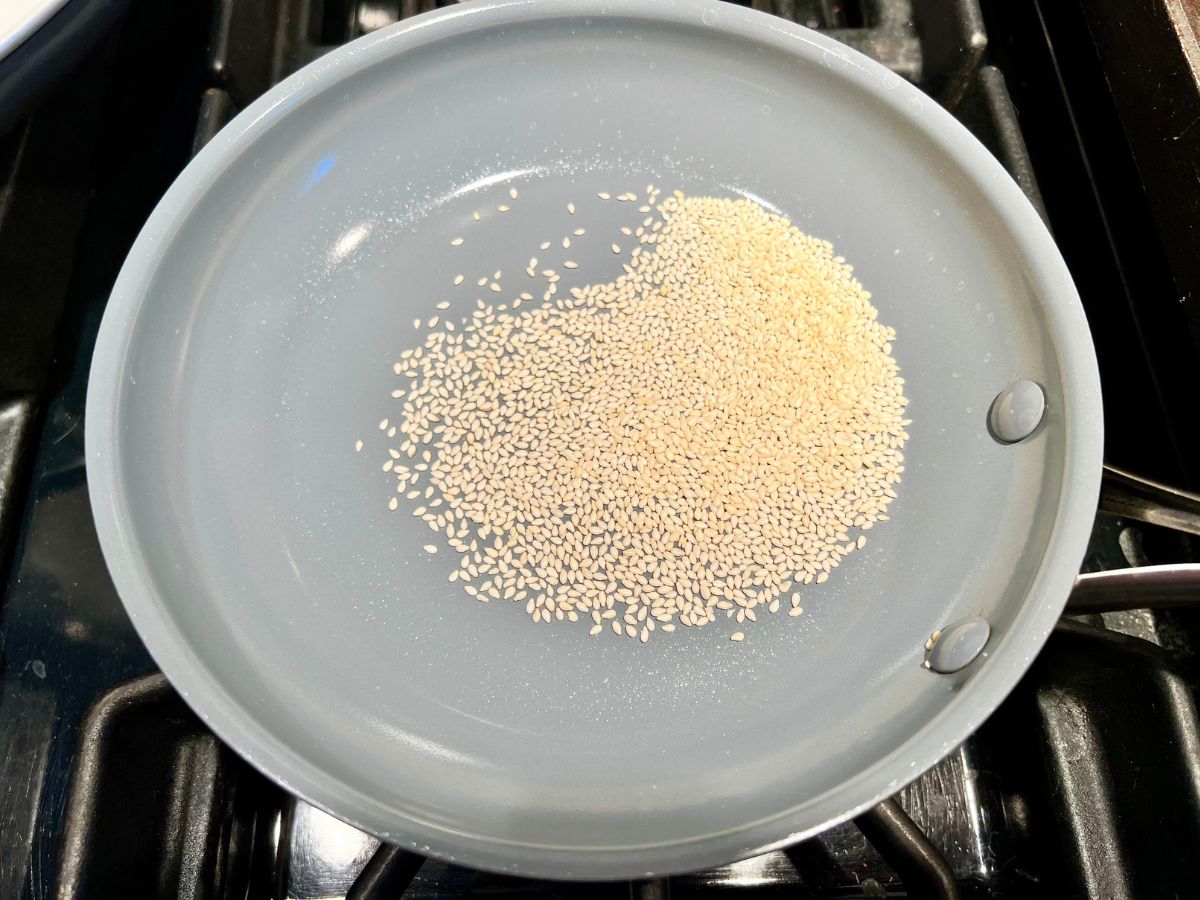 Sesame seeds added to a skillet to be toasted.