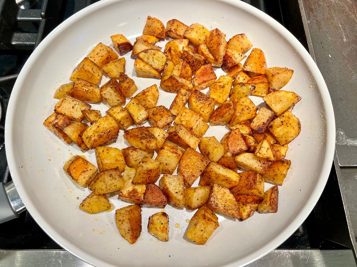 Baked potato pieces added to a skillet to crisp up.