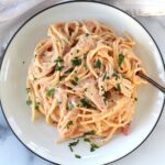 Slow Cooker Chicken and Spaghetti in a creamy cheesy sauce on a plate with a fork on a marble counter.