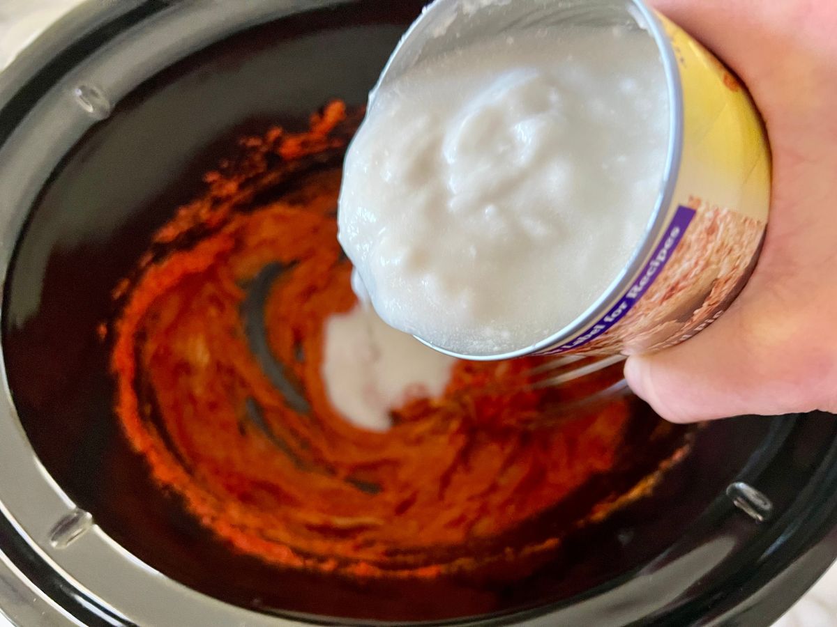 Coconut milk being added to the peanut sauce mixture for Slow Cooker Satay Chicken.